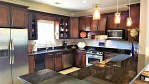 Una cocina moderna con armarios de madera oscura, electrodomésticos de acero inoxidable y una isla de granito.