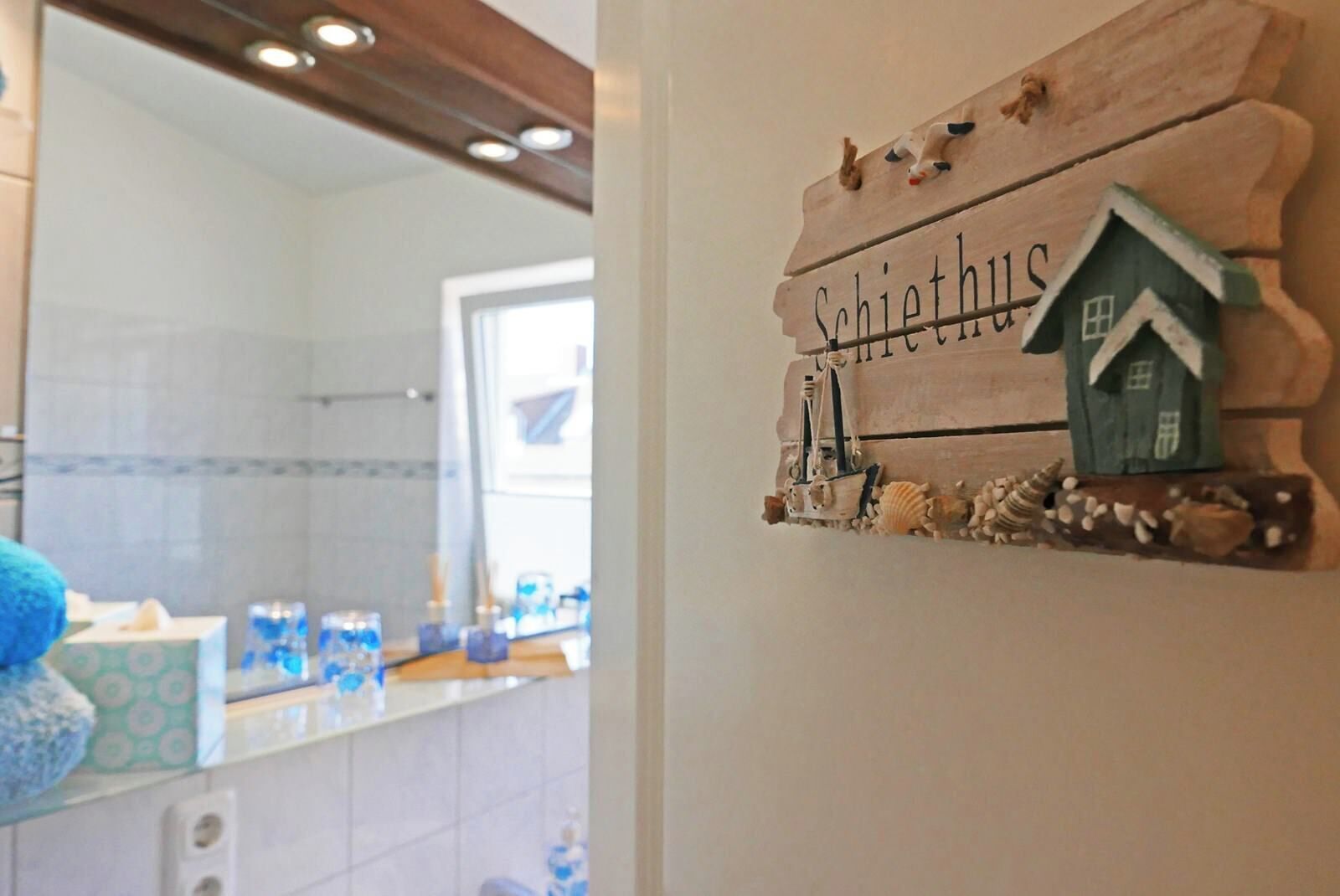 Een badkamer met een spiegel, een wastafel en een handdoekhouder.