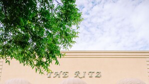 A building with a sign reading "THE RITZ" and a white car parked in front.