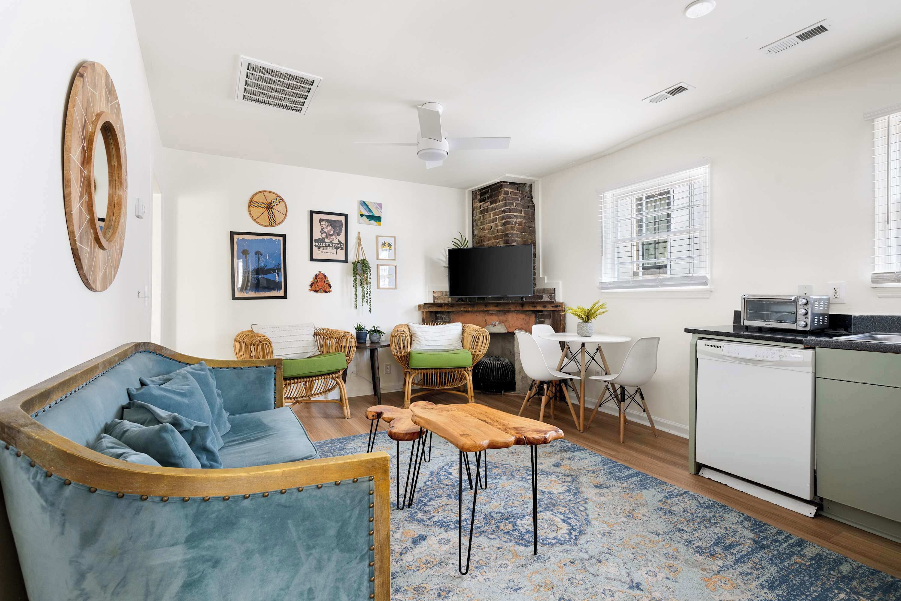A living room with a sofa, chairs, a coffee table, a fireplace, and a kitchen area with a dishwasher.