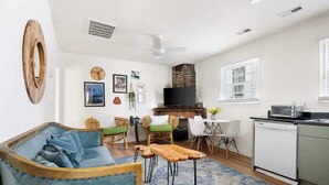 A living room with a sofa, chairs, a coffee table, a fireplace, and a kitchen area with a dishwasher. - Walk Everywhere! Cannon St Retreat! (Charleston)