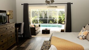 A bedroom with a bed, a dresser, a television, a ceiling fan, a window with curtains, and a view of a swimming pool. - Breathtaking 3 Bedroom 2 Bath Private Pool Home in Punta Gorda FL (Punta Gorda)