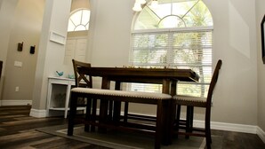 A dining area with a wooden table and benches, a chandelier, and a window with blinds. - Breathtaking 3 Bedroom 2 Bath Private Pool Home in Punta Gorda FL (Punta Gorda)