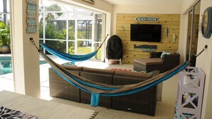 A living room with a hammock, a TV, and a sign that says "Beach House". - Breathtaking 3 Bedroom 2 Bath Private Pool Home in Punta Gorda FL (Punta Gorda)