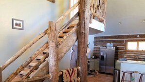 Ein rustikales Interieur mit einer Holztreppe, einer Küchenzeile und einem Essbereich.