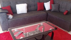 A living room with a grey sectional sofa, a glass coffee table, and a red rug. - Mtwapa Luxury Apartment by Blodriff Hospitality (Mtwapa)