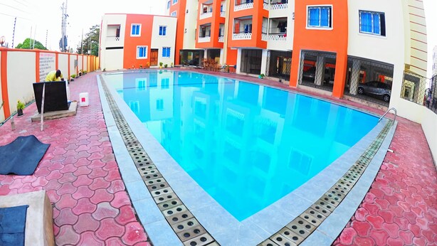 A swimming pool with a tiled deck, surrounded by multi-story buildings with balconies. - Mtwapa Luxury Apartment by Blodriff Hospitality (Mtwapa)