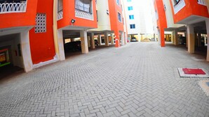 An open courtyard with a patterned brick floor, surrounded by buildings with orange and white facades. - Mtwapa Luxury Apartment by Blodriff Hospitality (Mtwapa)