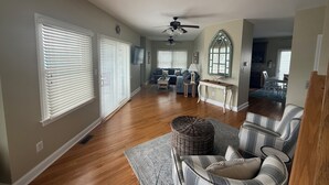 A spacious living room with hardwood floors, a ceiling fan, and a dining area with a table and chairs.