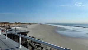 A beach with a wooden walkway and a metal railing.