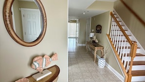 A hallway with a wooden console table, a mirror, and a staircase.