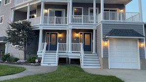 A two-story residential building with a front porch, multiple balconies, and a garage.