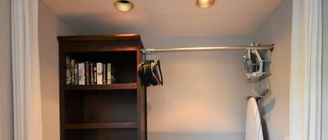 Une pièce de taille modeste avec un plancher en bois, une armoire en bois foncé dotée de plusieurs étagères, un petit radiateur noir et un autre radiateur.