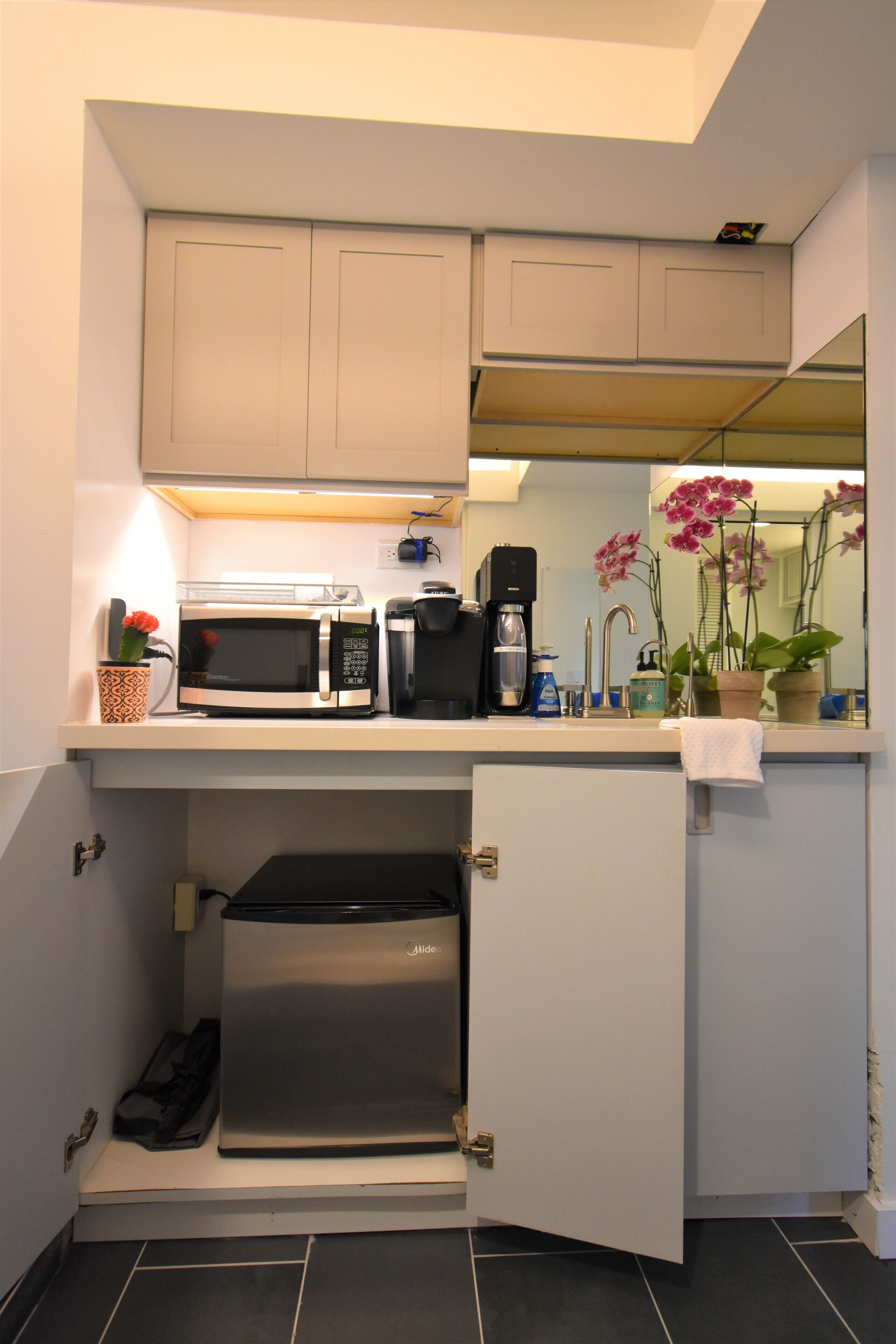 A compact kitchen with a microwave, coffee maker, and a small refrigerator.