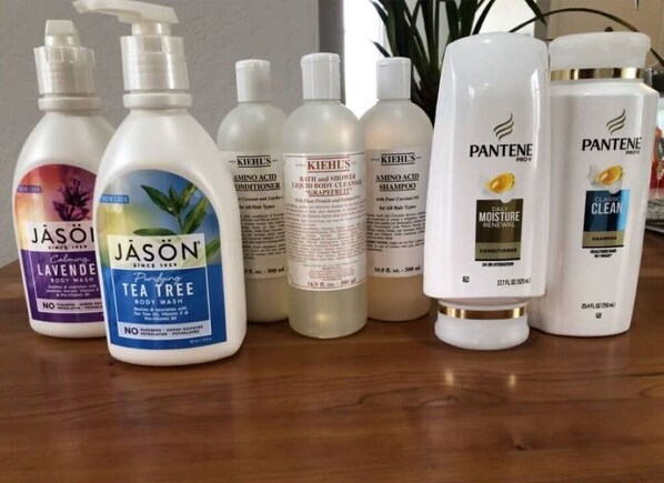 Diverse persoonlijke verzorgingsproducten, zoals douchegel, shampoo en conditioner, op een houten oppervlak.