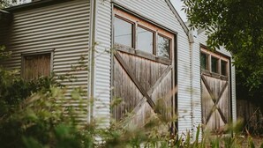 A rustic barn with corrugated metal siding and wooden doors. - The Stables Daylesford ~ Incredible Property! (Daylesford)