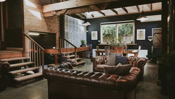 A spacious living area with a leather sofa, wooden staircase, and a dining table. - The Stables Daylesford ~ Incredible Property! (Daylesford)