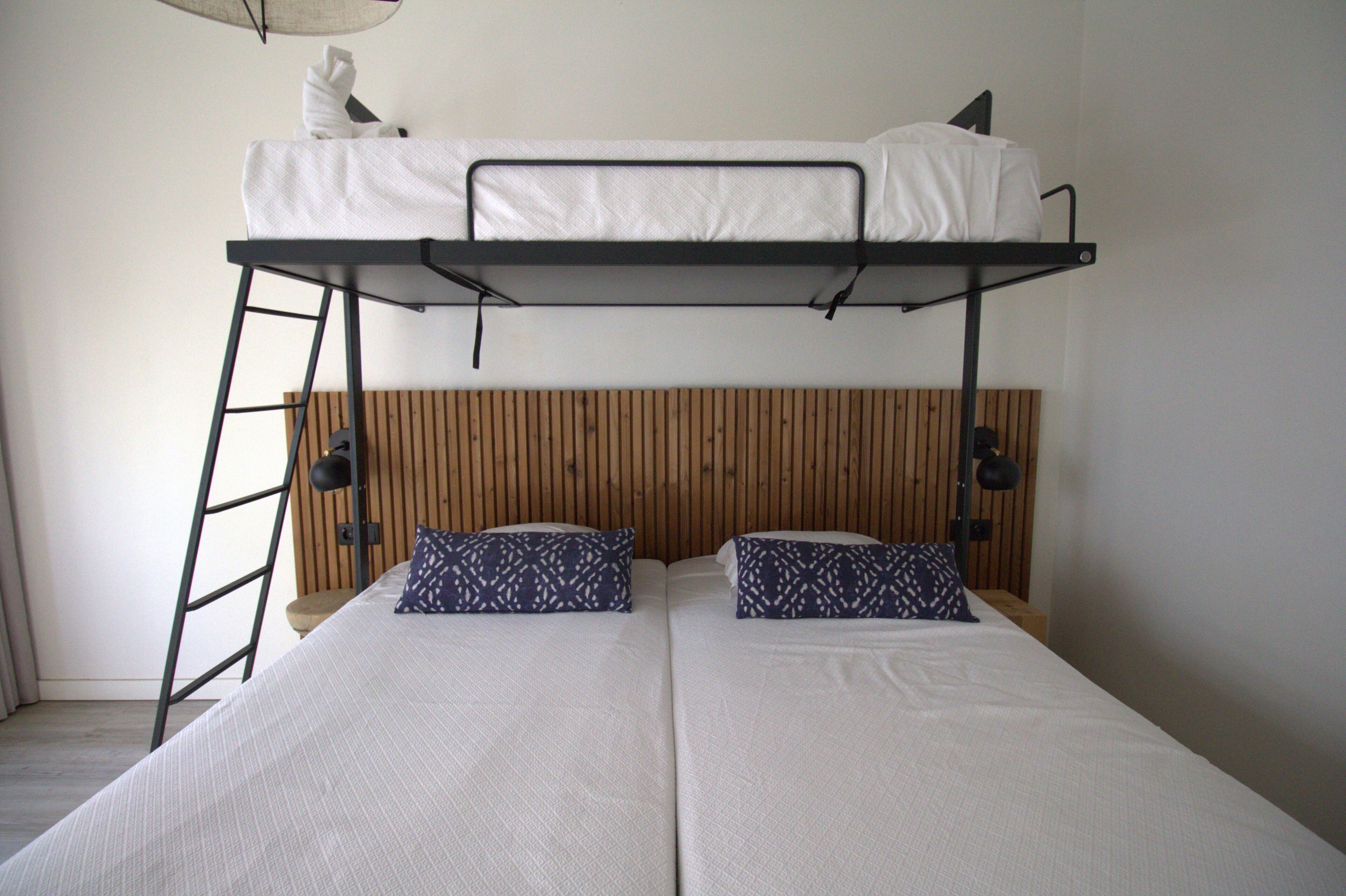 A bunk bed with a wooden headboard, two pillows, and a ladder.