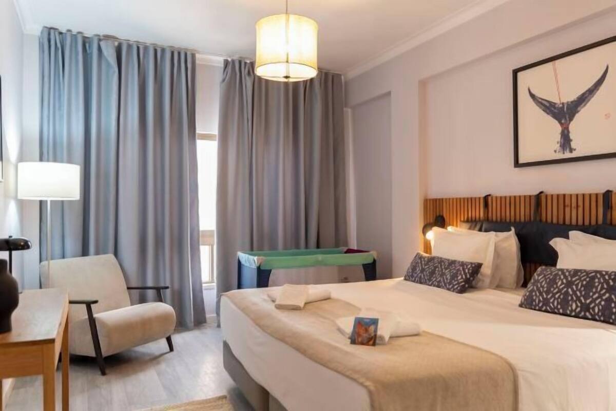 Une chambre d’hôtel avec un lit, une chaise, un bureau, une lampe et un tableau au mur.