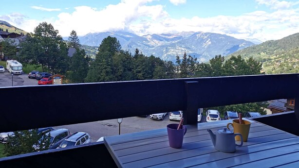A balcony with a view of a parking area and mountains.