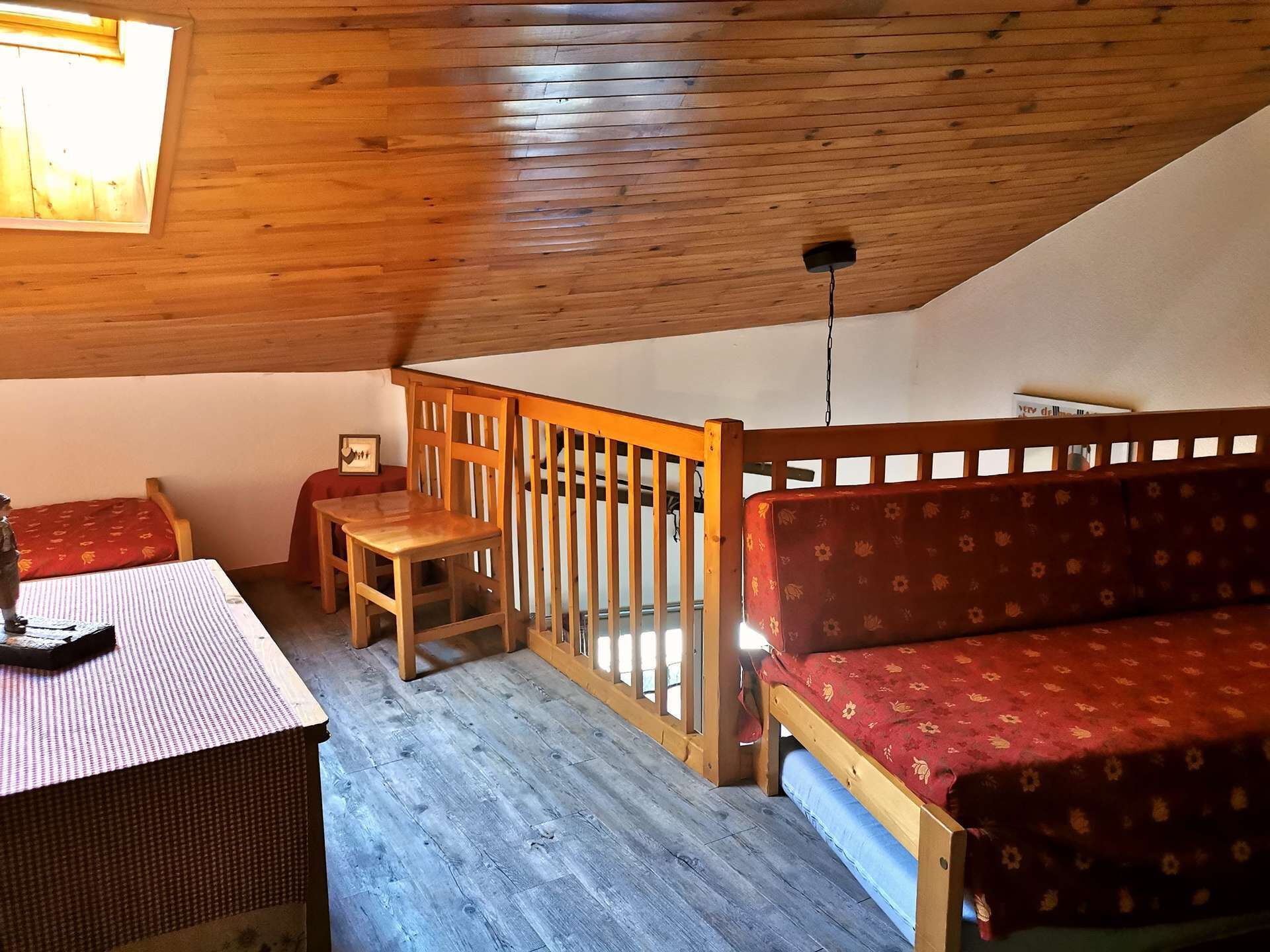 Una habitación acogedora con techo de madera, un sofá, una mesita y una cama con ropa de cama estampada.