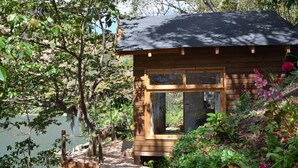 Een houten chalet met een raam en een klein terras dat uitkomt op een steiger.