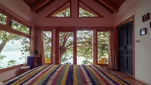 Een kamer met een groot bed, uitzicht op het meer en een deur naar buiten.