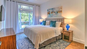 Ein Schlafzimmer mit einem Bett, einem Nachttisch, einer Lampe, einem Deckenventilator und einem Fenster mit Vorhängen.