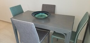 Een eettafel met een kom erop, omringd door vier stoelen.
