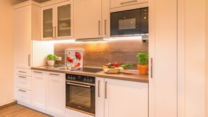 A modern kitchen with white cabinets, a built-in oven, a microwave, and a sink. - Mohnblume 65m² ***** (Palling)