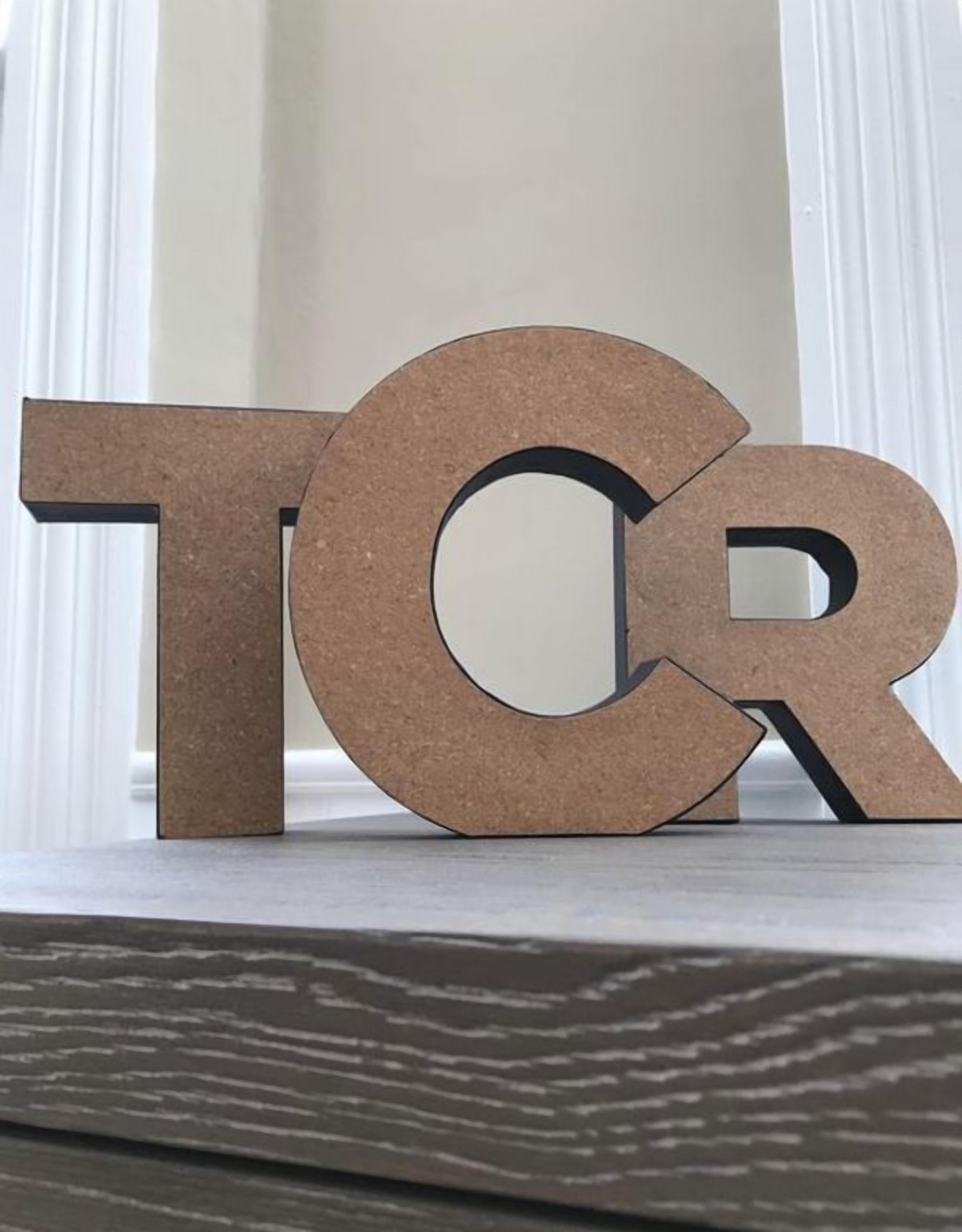 A cork sign with the letters "TOR" on a shelf.