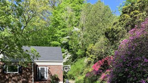 A gravel driveway leading to a brick house with a basketball hoop. - Bear Mountain House. (Philipstown)