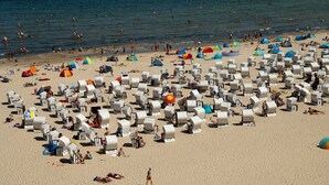 A beach with numerous white beach chairs and umbrellas, some tents, and people swimming in the water. - Baltic Building, Apartment 12, Balcony, Elevator, Central Location (Sellin)