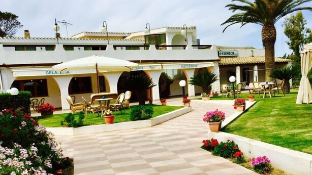 A courtyard with outdoor seating, a pharmacy, and a restaurant. - Complesso Il Saraceno (Maracalagonis)