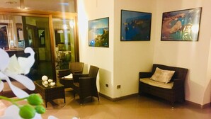 A hotel room with a seating area, a sofa, and a table with chairs. There are three framed pictures on the wall. - Complesso Il Saraceno (Maracalagonis)