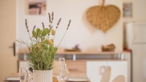 A dining table with a vase of flowers, glasses, and plates. - Cozy apartment in Njivice with WiFi (Njivice)