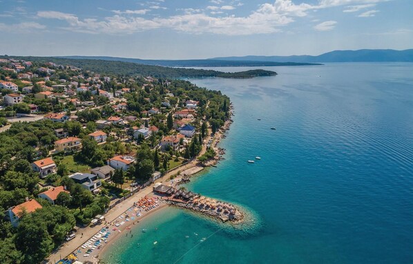 An aerial view of a coastal town with a beach, houses, and boats.