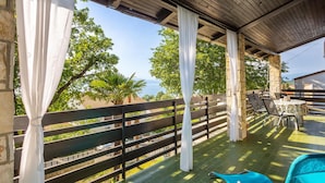 An outdoor patio with a wooden fence, a covered seating area, and a view of the sea. - Cozy apartment in Njivice with WiFi (Njivice)