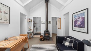 Una sala de estar acogedora con chimenea, una zona de comedor con mesa y sillas de madera, y una cocina al fondo.