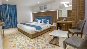 A modern hotel room with a large bed, a desk, a chair, and a mirror.