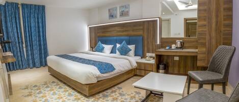 A modern hotel room with a large bed, a desk, a chair, and a mirror.