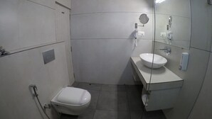 A small, modern bathroom with a toilet, sink, and mirror. - Pride By Samrat (Jabalpur)