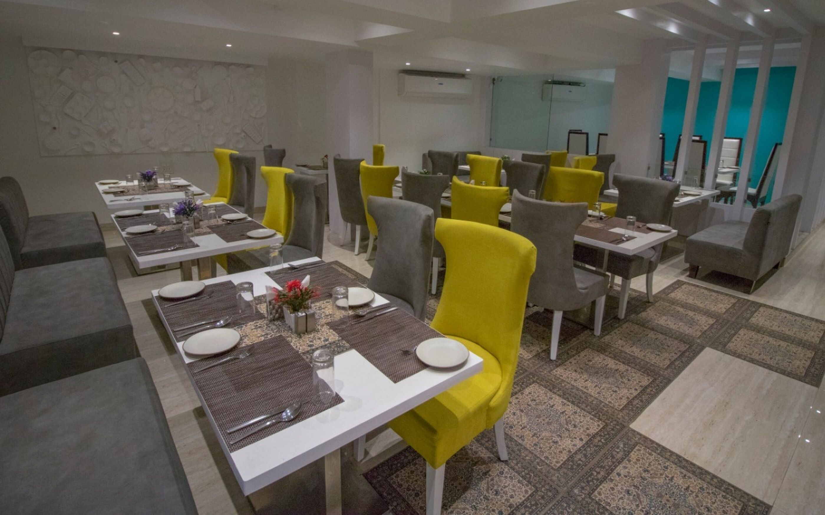 Un espace repas moderne, doté de plusieurs tables et chaises, dont certaines sont recouvertes d’un tissu jaune.