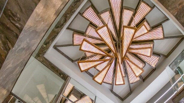 A modern interior with a glass staircase and a unique ceiling light fixture. - Pride By Samrat (Jabalpur)