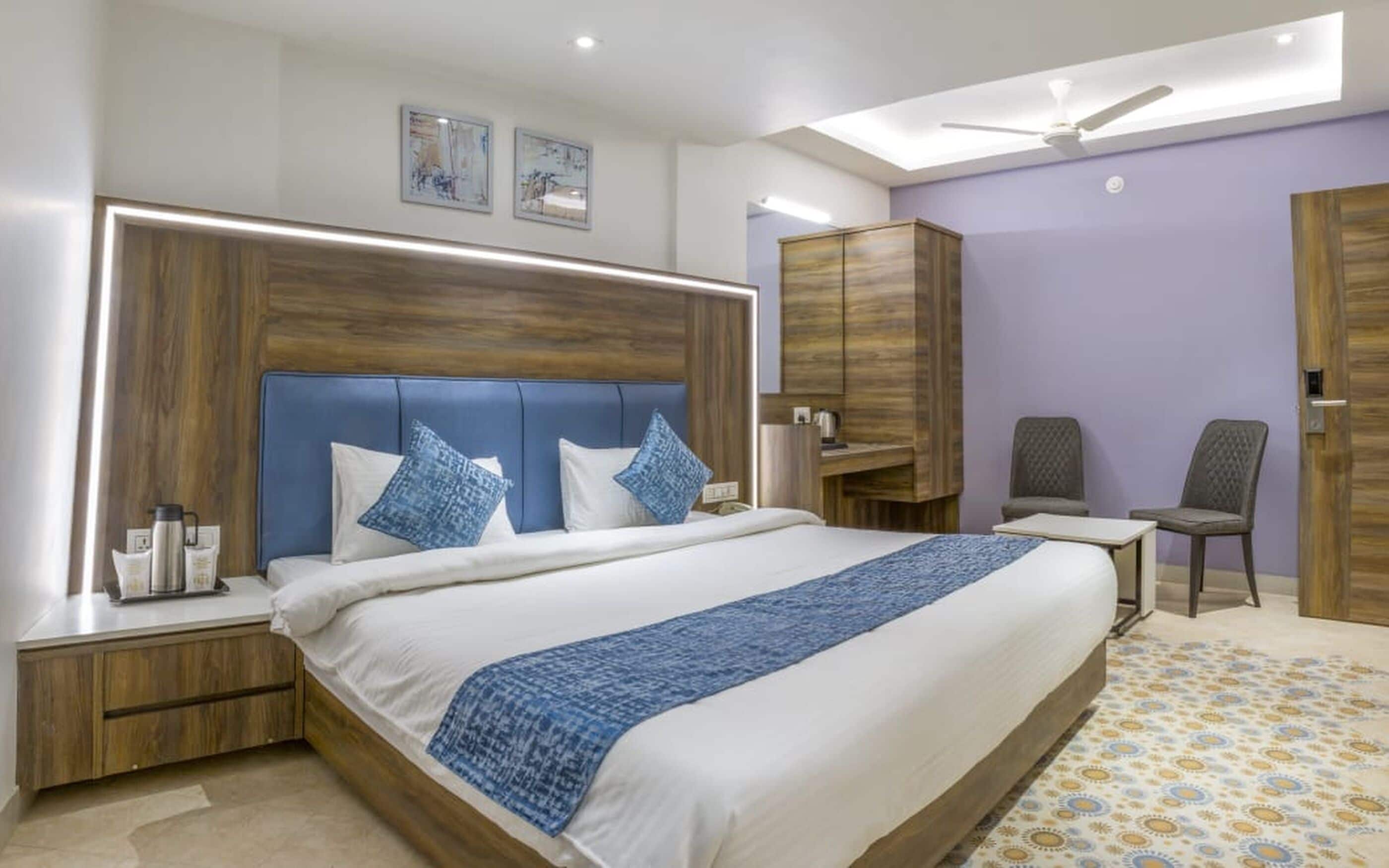 A modern hotel room with a large bed, a desk, a wardrobe, and a ceiling fan.
