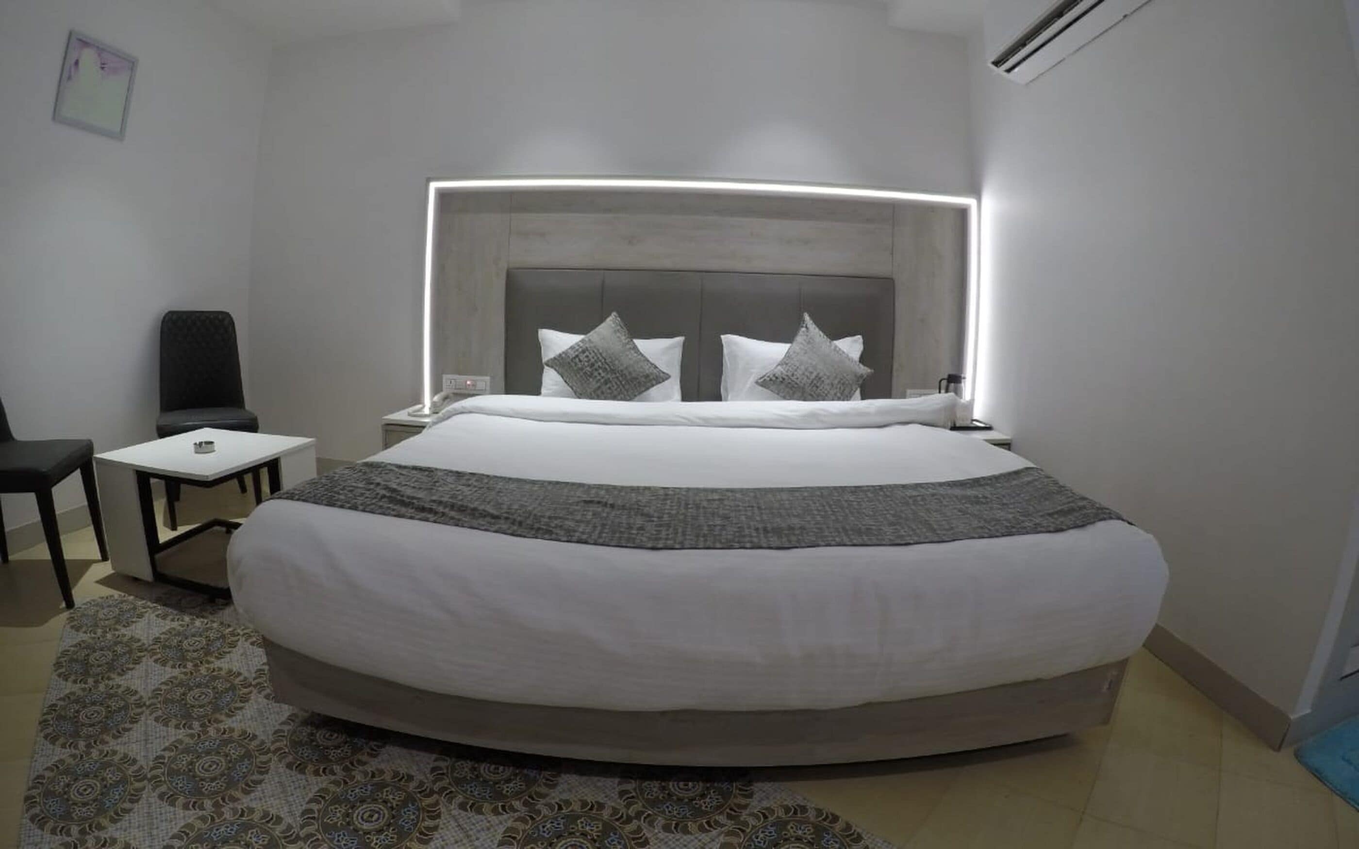A modern hotel room with a large bed, bedside tables, a desk, and a chair.