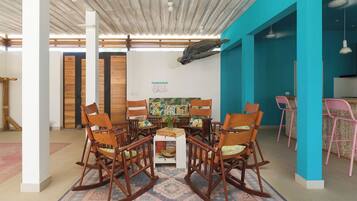 Une pièce avec une table centrale entourée de fauteuils à bascule, un tapis à motifs et un mur orné d’un poisson décoratif.