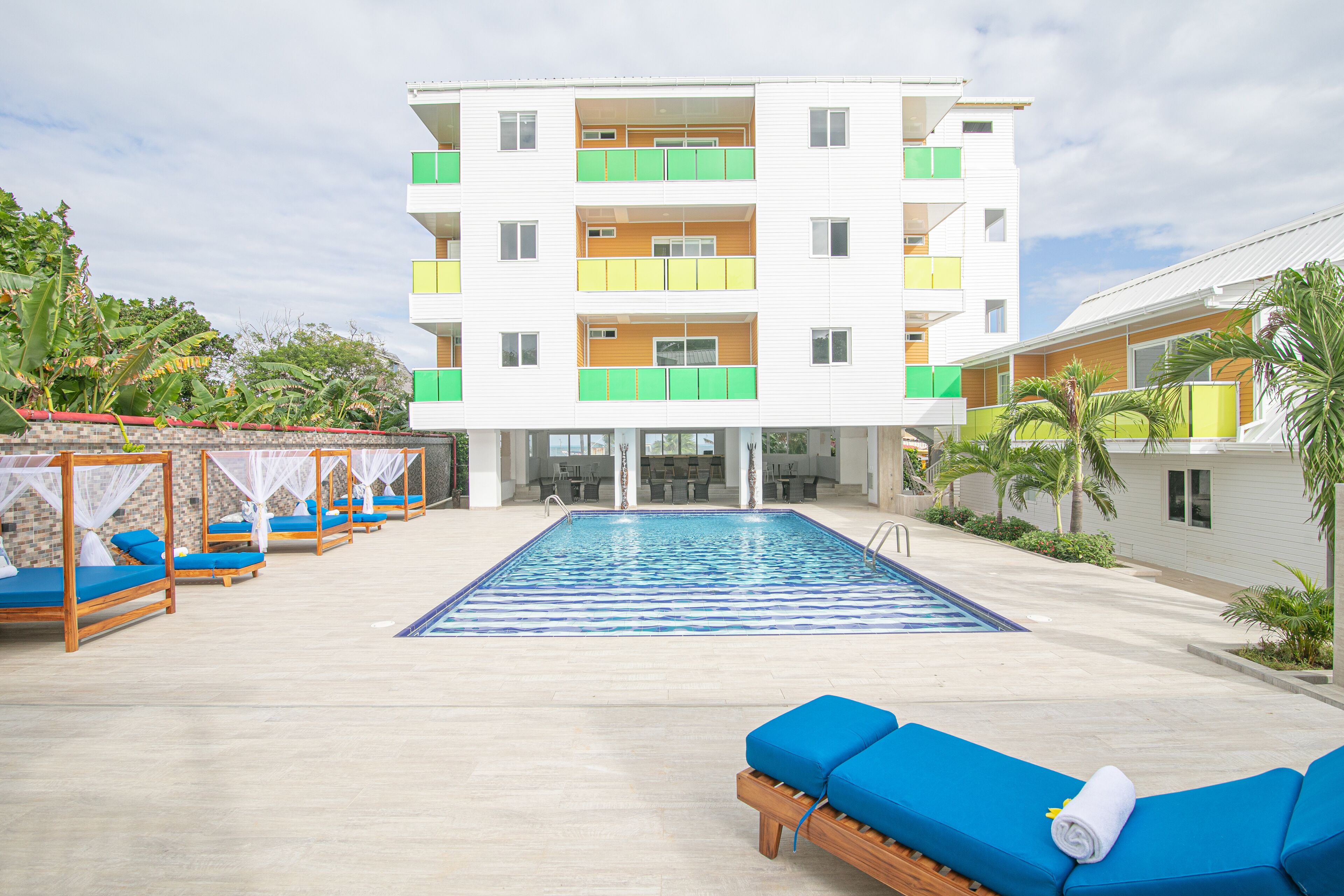 A hotel with a swimming pool, outdoor seating, and a multi-story building with balconies.