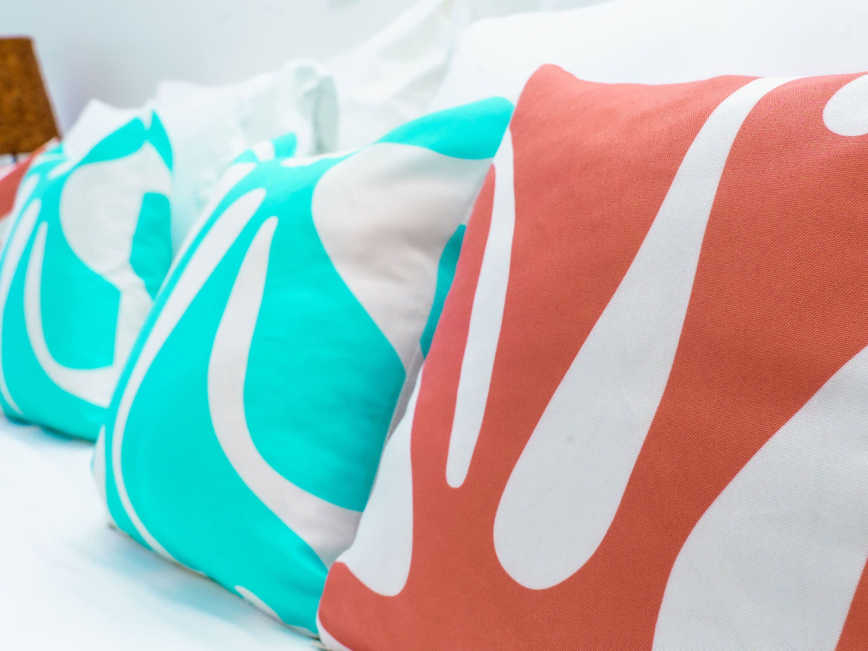 A row of pillows with a white and turquoise pattern.