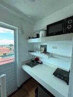 Cocina compacta con microondas, hervidor y un refrigerador pequeño.